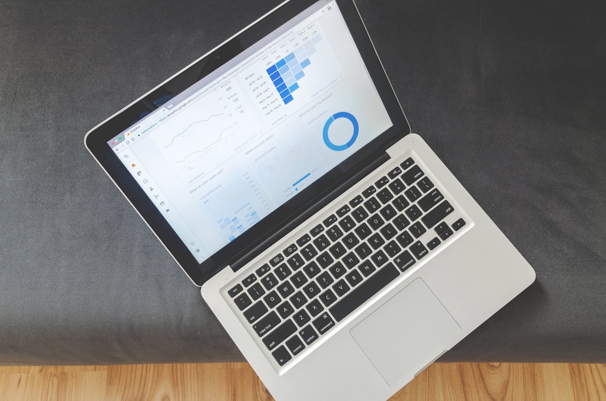 An overhead view of an open laptop showing an analytics dashboard with line, bar, and donut charts